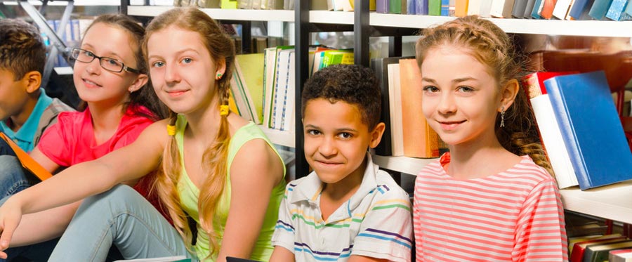 diverse children sitting in front of library books